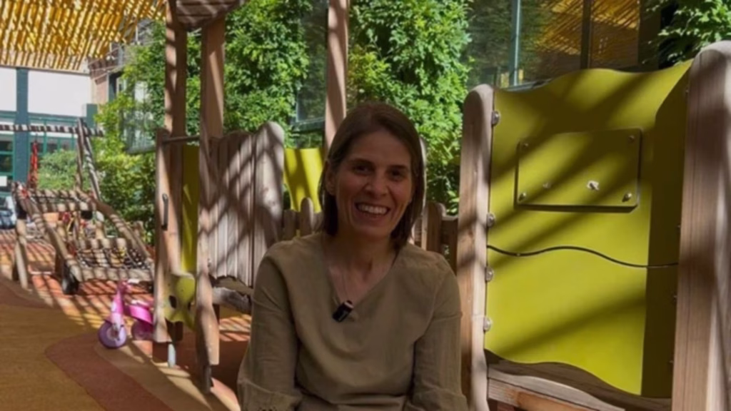 Carmen Molina sitting outside in the yard smiling and facing the camera.