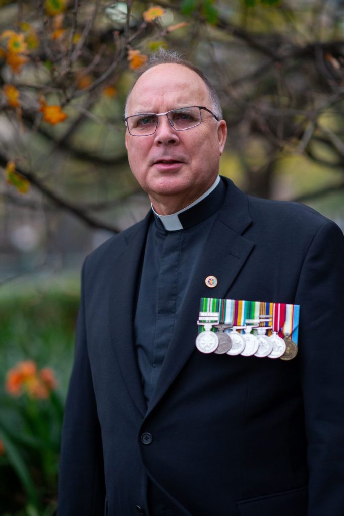 Bishop-elect Stuart Hall recently appointed Bishop for the Military Ordinariate standing wearing medals on his left lapel.