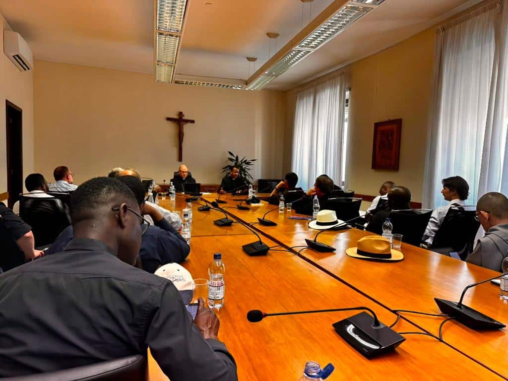 Students around table studying canon law. Archbishop Randazzo at the head of the long table.