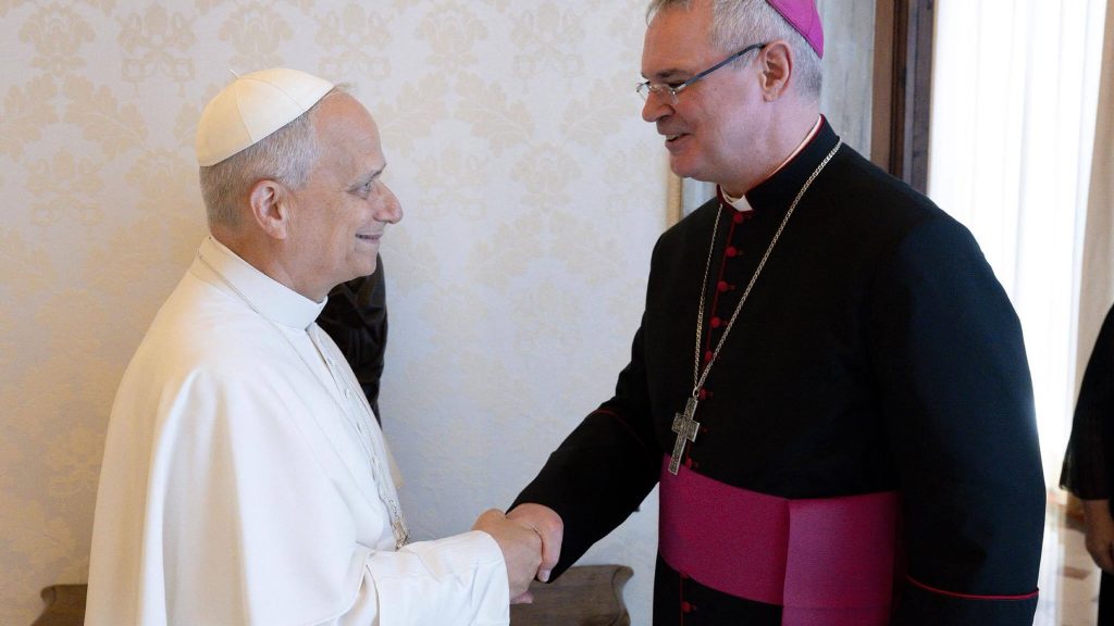 Pope Leo XIV on the left and Archbishop Comensoli shaking his hand on the right.