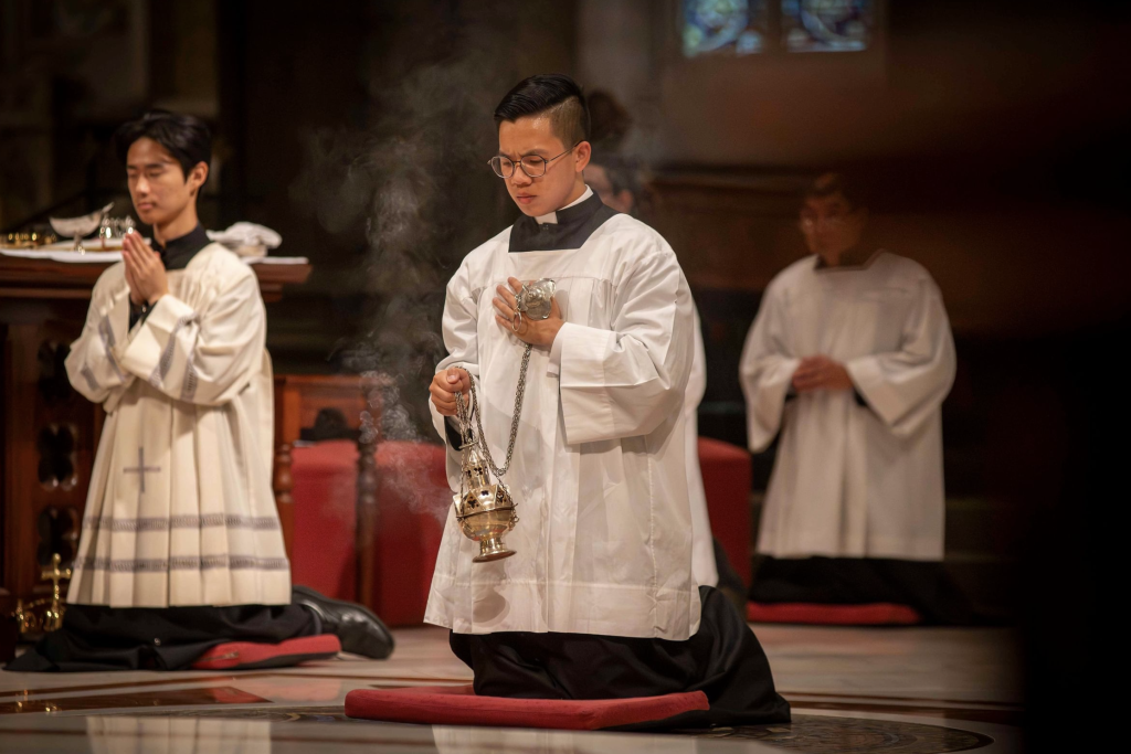 Seminarian Liam Bui kneels with a thurible during the Easter Vigil Mass at St Patrick's Cathedral, Melbourne, pursuing his vocation to the priesthood.