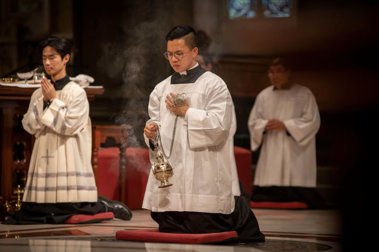 Seminarian Liam Bui kneels with a thurible during the Easter Vigil Mass at St Patrick's Cathedral, Melbourne, pursuing his vocation to the priesthood.